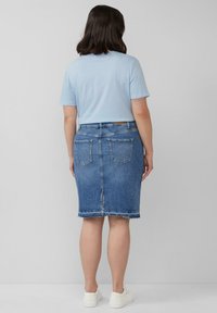 Jeans-Bleistiftskirt mit ausgefranstem Saum, hellblauer Farbe und Gesäßtaschen. Kombiniert mit einem enganliegenden, hellblauen T-Shirt und weißen Sneakers.