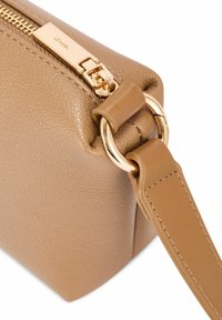 Skórzana torba w kolorze tan, o wyraźnej formie, z złotym zamkiem i okuciami oraz płaskim paskiem z detalicznym przeszyciem.