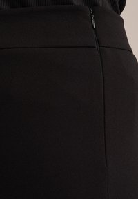 Černá sukně se strukturovanou látkou, s nenápadným zipem na boku a hladkým pasem pro elegantní vzhled.