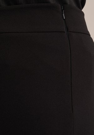Černá sukně se strukturovanou látkou, s nenápadným zipem na boku a hladkým pasem pro elegantní vzhled.