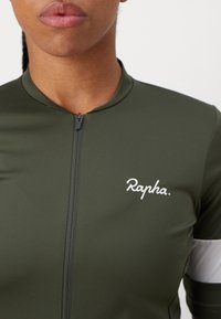 Grünes Fahrradtrikot aus glattem, dehnbarem Material. Verfügt über einen Frontreißverschluss, ein gesticktes weißes "Rapha"-Logo und kontrastierende graue Streifen an den Ärmeln.