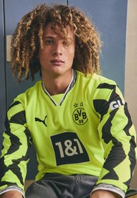 Fényes sárga kapusmez fekete cikk-cakk mintázattal, kerek gallérral és a PUMA és Borussia Dortmund logóival.