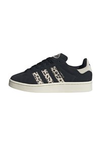 Schwarze Adidas Campus Sneaker mit weißer Sohle, Leopardenmuster auf den drei Streifen, schwarzen Schnürsenkeln und weißem Fersenbereich mit Logo.