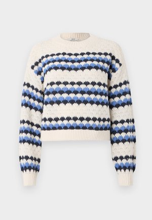Pull en tricot crème avec des rayures en zigzag bleues et noires, présentant un col rond et des poignets côtelés. Design court avec un tissu texturé.