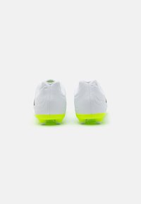 Botas de fútbol blancas con una textura suave, que presentan una suela de color verde neón, un diseño tradicional con cordones y acentos negros a los lados.