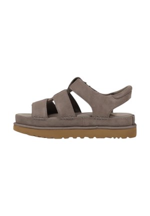 Sandalias de ante gris con tres tiras superiores, diseño de talón abierto y suela de goma beige con un patrón de agarre texturizado.