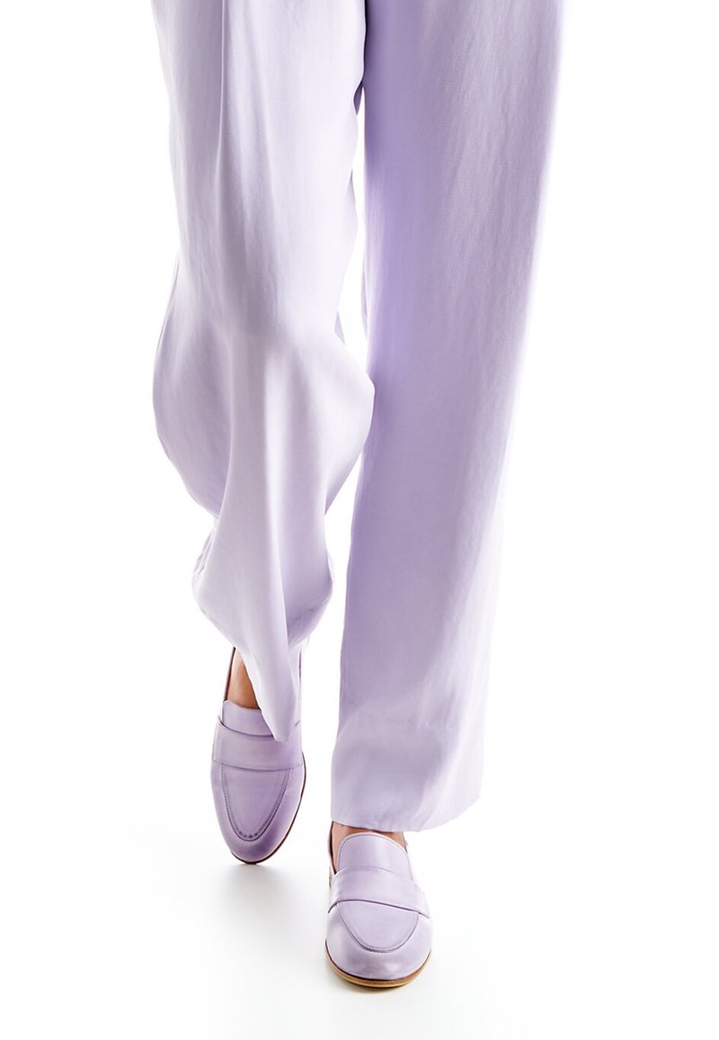Mocassins en cuir lavande avec une finition lisse, dotés d'un détail surpiqué sur l'empeigne et d'un bout arrondi. Portés avec un pantalon lilas ample.