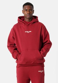 Sudadera burdeos con un bolsillo canguro, texto en blanco "SIXTH JUNE PARIS" en el pecho, con capucha ajustable y puños acanalados.