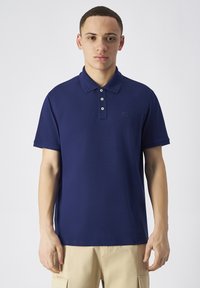 Granatowa koszulka polo z krótkim rękawem, zapinana na trzy guziki, z dyskretnym logo na lewej piersi. Wykonana z gładkiego, lekkiego materiału.