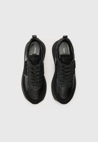 Baskets noires avec un corps en cuir lisse, des accents en textile pailleté sur la languette et des semelles en caoutchouc texturé, avec des lacets noirs.