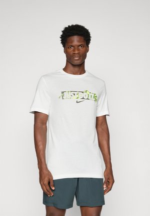Biela tričko s grafikou "JUST DO IT" v zelenej a šedej farbe a logom Nike, s krátkymi rukávmi a dizajnom s okrúhlym výstrihom.