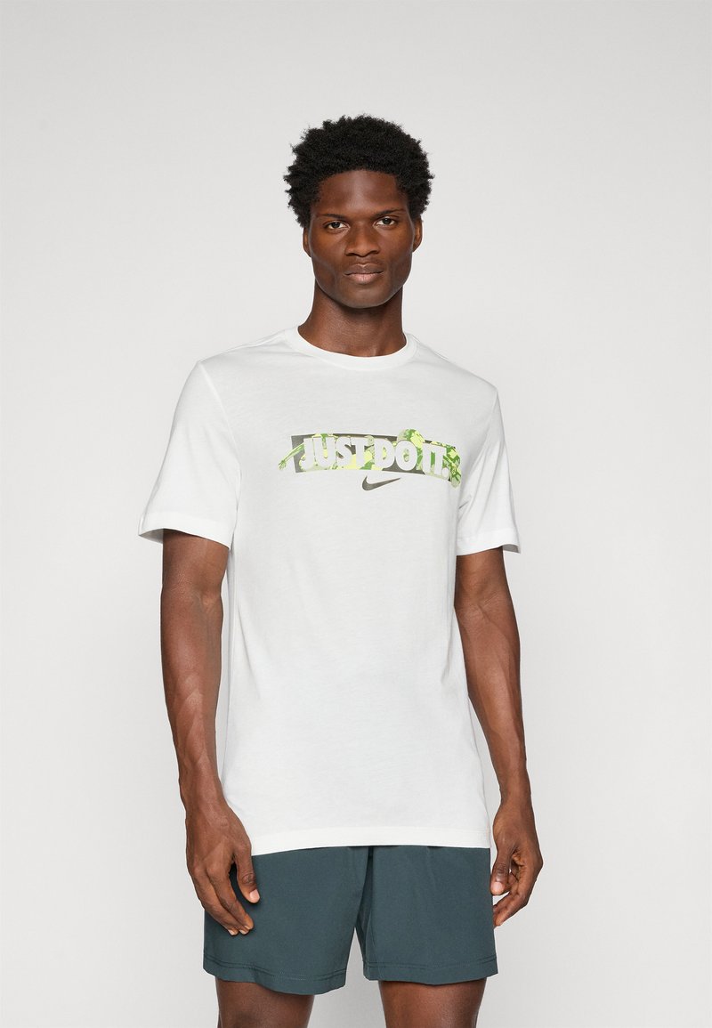Biela tričko s grafikou "JUST DO IT" v zelenej a šedej farbe a logom Nike, s krátkymi rukávmi a dizajnom s okrúhlym výstrihom.