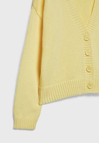 Yellow knitted cardigan with a v-neck, ribbed cuffs, five yellow buttons, and a relaxed fit. Soft texture with a lightweight appearance.