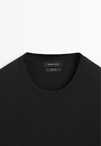 Pull en coton noir col rond avec col côtelé et étiquette Massimo Dutti cousue à l'intérieur de l'encolure.