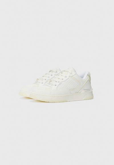 Zapatillas de cuero blancas con paneles laterales texturizados, cordones redondos y una suela de goma ligeramente translúcida. Presenta sutiles acentos de marca.