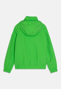 Vihreä kevyt toppatakki, jossa on huppu, joustavat hihansuut ja alareuna. Sileä pinta, yksinkertainen muotoilu eikä näkyviä metalliosia tai koristeita.