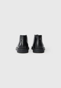 Sorte lær ankle boots med en glat overflade, afrundet tå, subtile syninger og en lav gummisål. Branding på hælen.