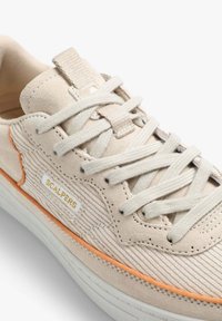 Baskets en suède beige avec lacets en coton, rayures texturées, accents orange et détail en or du logo. La semelle en caoutchouc plate complète le design.