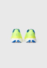 Baskets de course vert lime avec des accents bleus, tige en mesh, semelle blanche rembourrée et détails réfléchissants au niveau du talon et des côtés.