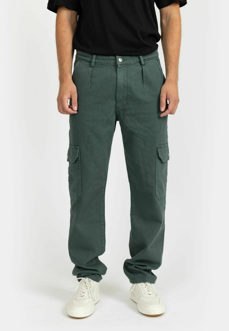 Gröna cargobyxor i bomull, med sidfickor, en avslappnad passform och en slät textur. Bärs med vita sneakers och en svart t-shirt.