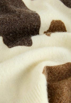Sweter dzianinowy w odcieniach kremu i brązu o miękkiej teksturze. Posiada abstrakcyjne łatki brązowe na jasnym tle. Miękki, puszysty materiał.
