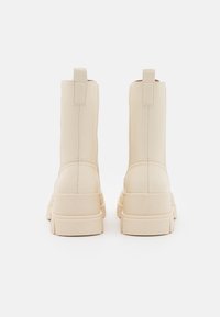 Stivaletti alla caviglia beige con un design elegante e suola spessa. Realizzati in pelle liscia, con linguette posteriori per una facile calzata.