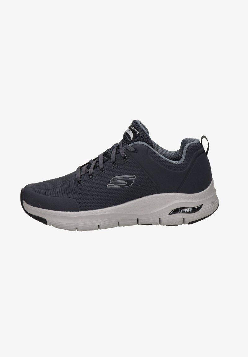 Zapatilla deportiva con una parte superior de malla gris, detalles en gris claro y una suela blanca. Cuenta con un acolchado en el cuello y una lengüeta trasera para ponerlas fácilmente.