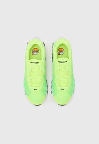 Neon gröna träningsskor med en strukturerad ovandel, traditionell snörning, Nike swoosh-logotyp och svarta sula accenter.