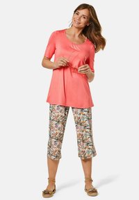 Koraal kleurig jersey top met korte mouwen en een gathered halslijn, gecombineerd met cropped broeken in een bloemenprint. Bevat decoratieve bloemmotieven.