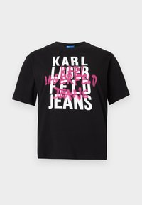 T-shirt de algodão preta com letras brancas em destaque a dizer "KARL LAGERFELD JEANS", com um efeito de spray rosa sobre certas letras.