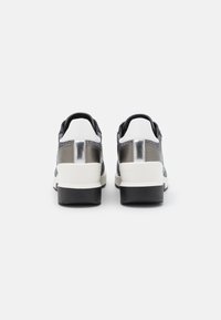 Sneaker sportive nere e argento con tomaia testurizzata, intersuola bianca e suola esterna in gomma nera. Presenta dettagli metallici sul tallone.