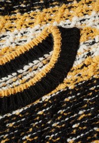 Maglione lavorato a maglia con un mix di filati neri, gialli e bianchi. Motivo testurizzato con colletto a coste nero e segmenti di colore a contrasto.