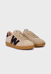 Zapatillas de ante beige con acentos de cuero negro, logotipo 'W' texturizado y suela plana de goma color beige. Presentan un diseño tradicional con cordones y lengüeta acolchada.