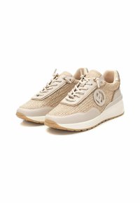 Zapatillas beige con paneles de malla y cuero suave, que presentan un logo redondo en el lateral, cordones planos y una suela de goma acolchada.