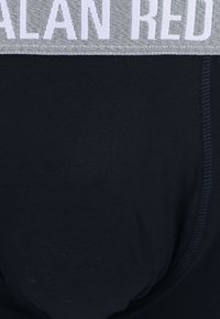 Black brief with stretchy fabric, featuring a grey elastic waistband with white lettering, seamless edges, and a smooth texture.