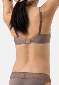 Ruskea rintsikka, jossa on säädettävät hihnat ja pitsikorostus takana. Silkkinen kangas ja hakaskiinnitys näkyvät.