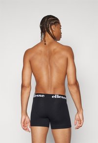 Schwarze Boxershorts mit einem weißen "ellesse"-Logo am Bund, glatter Stoffstruktur und einer figurschmeichelnden Passform.