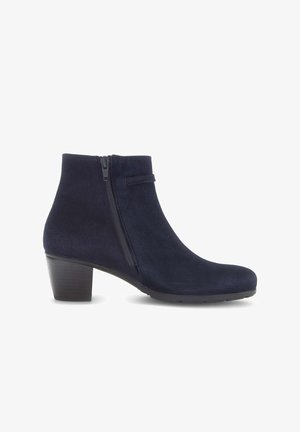 Botte chelsea en daim bleu marine avec fermeture à glissière sur le côté, bout rond et petit talon empilable. Texture lisse avec une silhouette élégante.