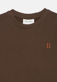 Καφέ βαμβακερό μπλουζάκι με στρογγυλή λαιμόκοψη, με πορτοκαλί κεντητό διακοσμητικό "II" στο αριστερό μέρος. Μαλακή υφή και απλός σχεδιασμός.