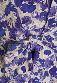 Tessuto per abito floreale con un motivo viola e beige, dotato di un dettaglio in vita legato e realizzato in materiale morbido e texture.