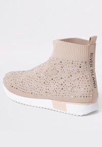 Beige ankelskor med en stickad ovandel, försedda med rhinestones, vit sula och ljusrosa detaljer. Märkt med "RIVER ISLAND" bakpå.