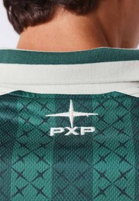 Dos d'un maillot de sport vert à motif avec un col blanc et un logo PXP brodé en blanc sous le cou.