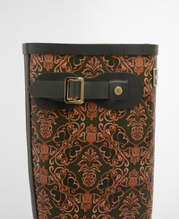 Green patterned bag featuring an ornate design in orange, with a black strap and gold hardware accents. Textured material and structured shape.