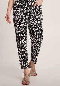 Zwarte en crèmekleurige gestreepte broek van een zachte, textuurstof, met een relaxte pasvorm en zijzakken. Gecombineerd met beige hakken.