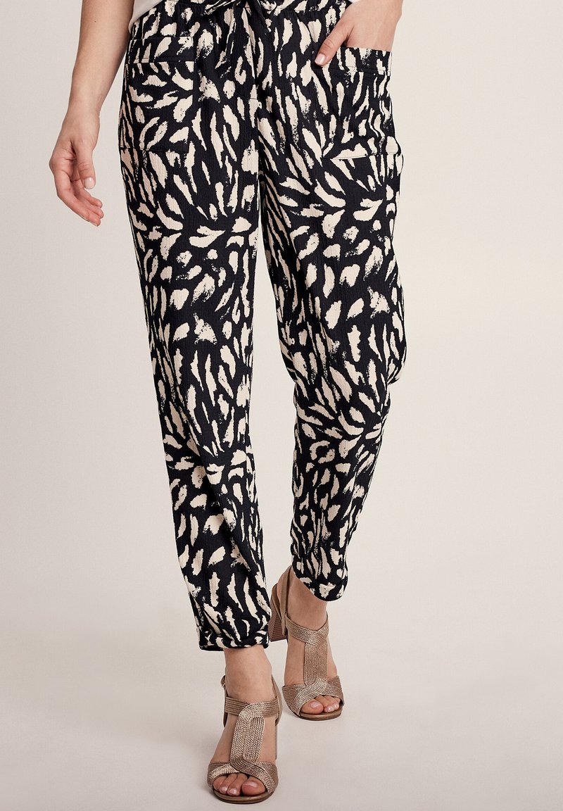 Zwarte en crèmekleurige gestreepte broek van een zachte, textuurstof, met een relaxte pasvorm en zijzakken. Gecombineerd met beige hakken.