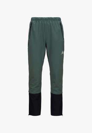 Pantalons de sport verts avec des accents noirs, taille élastique et poches zippées. Tissu doux et lisse avec des jambes fuselées et des zips aux chevilles.