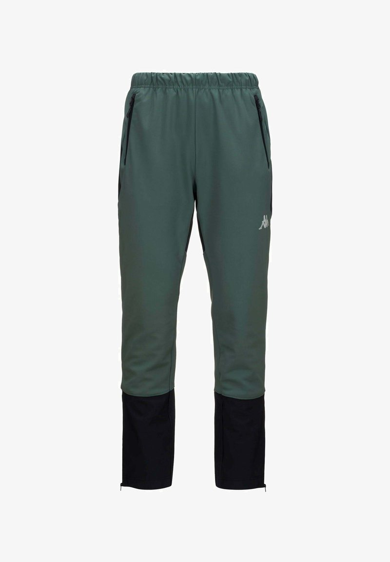 Pantalons de sport verts avec des accents noirs, taille élastique et poches zippées. Tissu doux et lisse avec des jambes fuselées et des zips aux chevilles.