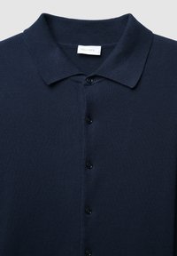 Marineblauer Strickcardigan mit Kragen, durchgehender Knopfleiste mit sechs schwarzen Knöpfen und gerippter Struktur im gesamten Stoff.