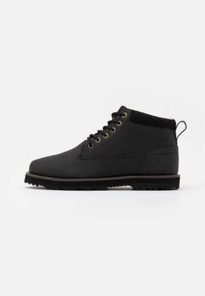 Bottine noire en cuir avec lacets sur le devant, col rembourré, languette au talon et semelle texturée pour une utilisation en extérieur.