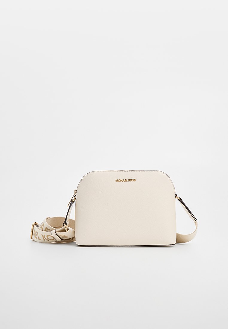 Bolso cruzado crema con forma redondeada, herrajes en tono dorado, logo grabado y correa ajustable con estampado. Fabricado con material texturizado.